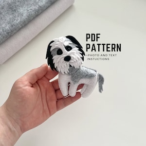 Puede incluir: Un patrón de perro de fieltro para coser un perro pequeño, gris y blanco con ojos negros. El patrón incluye instrucciones fotográficas y de texto. PDF PATTERN +PHOTO AND TEXT INSTRUCTIONS