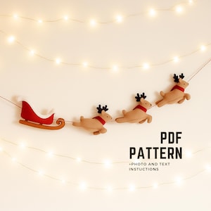 May include: A festive Christmas garland featuring a red sleigh and three reindeer with red scarves and black antlers. The garland is strung on a thin string, with the text "PDF PATTERN" and "+PHOTO AND TEXT INSTRUCTIONS" in black.