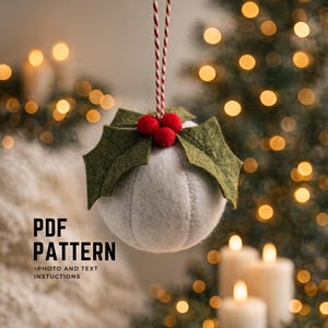 Puede incluir: Adorno navideño hecho a mano con forma de bola blanca cosida, adornado con hojas de acebo de fieltro verde y racimos de bayas rojas. El adorno cuelga de una cuerda roja y blanca. El texto en la imagen dice: "PDF PATTERN + PHOTO AND TEXT INSTRUCTIONS."