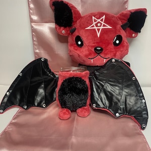 May include: Red plush bat with black wings and a pentagram on its forehead. The bat is wearing a black leather jacket with silver studs.