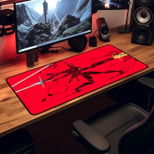 May include: A red gaming mouse pad with a black and white illustration of a robot with glowing blue lights. The robot is standing on a cracked surface with a red background.