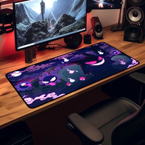 May include: A black and purple gaming mouse pad with a graphic of a cartoon ghost character. The character is surrounded by smaller ghosts and a graveyard setting.