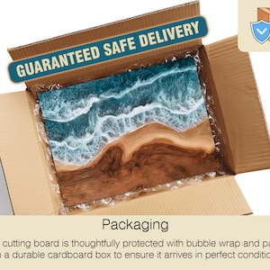May include: A wooden cutting board with a blue and white ocean wave design, inside a cardboard box. The box has the text "GUARANTEED SAFE DELIVERY". The packaging includes bubble wrap for protection.