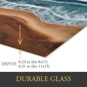 May include: Durable glass art piece showing a beach scene with ocean waves and sand. The depth is 0.61 cm for an 20.3x27.9 cm size and 0.79 cm for a 27.9x38.1 cm size. The artwork features a brown wooden base and a clear glass top.