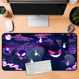 May include: A black and purple gaming mouse pad with a dark purple background and a design of a cartoon ghost with glowing pink eyes. The ghost is surrounded by other smaller ghosts and a mountain in the background. The mouse pad is on a wooden desk with a keyboard and a computer monitor.