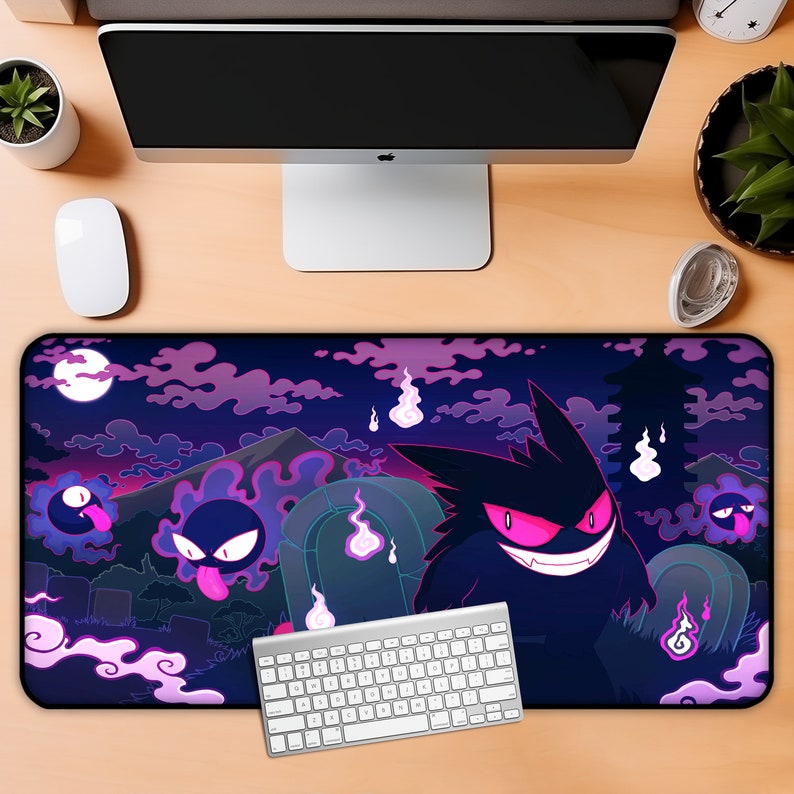May include: A black and purple gaming mouse pad with a dark purple background and a design of a cartoon ghost with glowing pink eyes. The ghost is surrounded by other smaller ghosts and a mountain in the background. The mouse pad is on a wooden desk with a keyboard and a computer monitor.