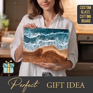 May include: A rectangular glass cutting board with a beach scene design. The top half features blue and white waves, while the bottom half depicts a brown sandy beach. The text "CUSTOM GLASS CUTTING BOARD" is in the upper right corner.