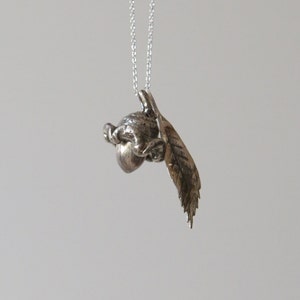 May include: A silver necklace with a detailed acorn charm and a leaf pendant.