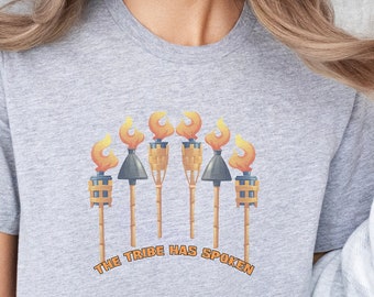 May include: A gray t-shirt with a graphic of five tiki torches with flames and the text "The Tribe Has Spoken".