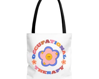 Puede incluir: Bolsa de tela blanca con un diseño circular de colores que dice "Occupational Therapy" con una flor rosa que contiene una cara sonriente en el centro.