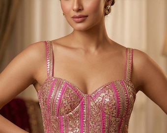 Peut inclure: Un haut style corset sans manches en rose fuchsia vif, doté de panneaux verticaux ornés de broderies dorées complexes et de paillettes scintillantes. Le vêtement présente un décolleté en cœur, des bretelles épaisses et un ourlet pointu.