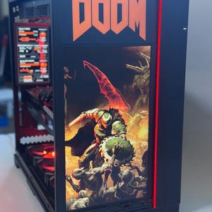 Könnte beinhalten: Schwarzer Computerturm mit dem Wort "DOOM" in orangefarbenen Blockbuchstaben. Die Frontplatte zeigt eine Grafik eines Kriegers, der gegen Dämonen kämpft. Ein roter Lichtstreifen verläuft die Seite entlang. Die internen Komponenten sind sichtbar.