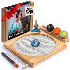 May include: A Zen garden kit with a bamboo tray, white sand, and decorative stones. The kit includes a small Buddha statue, a rake, and a brush. The box features a woman arranging a zen garden and the text "Zen Garden Kit".
