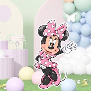 May include: A pink and white Minnie Mouse character cutout with a red bow and white polka dots. The character is standing on a green grassy surface with pastel colored balloons and a white cloud in the background.