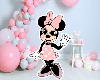 May include: A pink and black cartoon character with a bow, sunglasses, and a pink floral dress. The character is waving with a white glove. The background is a wall with a garland of pink and gray balloons.