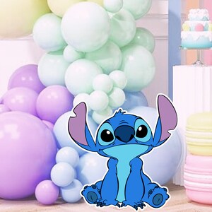May include: A blue cartoon character with large ears and a big smile, sitting in front of a backdrop of pastel colored balloons.