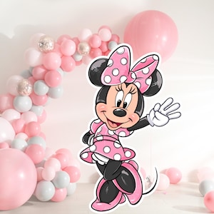 May include: A pink and white Minnie Mouse character cutout with a red bow and white polka dots. The character is standing in front of a balloon arch made of pink, white, and silver balloons.