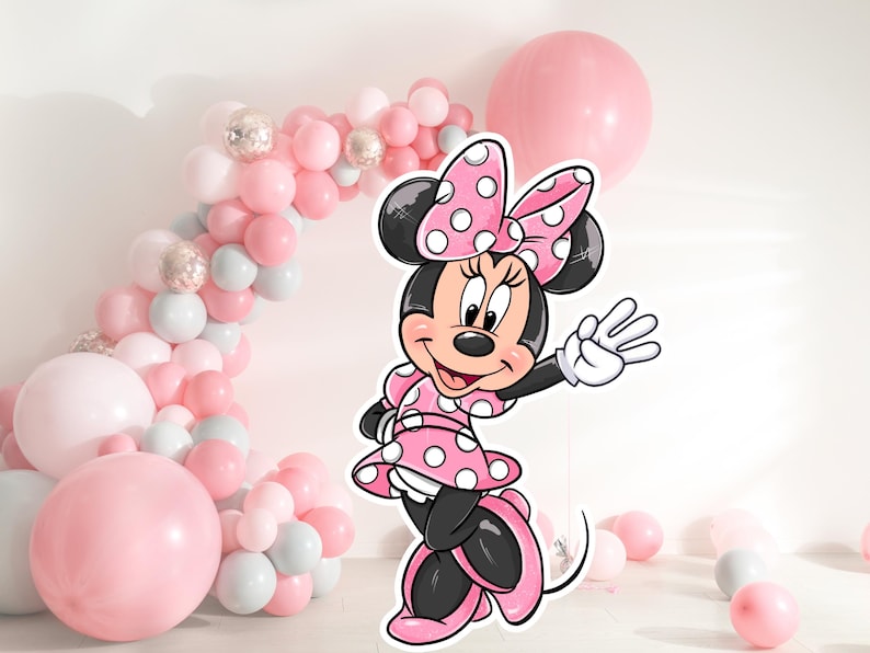 May include: A pink and white Minnie Mouse character cutout with a red bow and white polka dots. The character is standing in front of a balloon arch made of pink, white, and silver balloons.