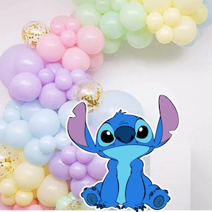 May include: A blue cartoon character with large eyes and a big smile, sitting in front of a pastel balloon arch. The balloons are in shades of pink, purple, blue, and yellow.