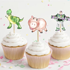 May include: Three cupcakes decorated with Toy Story characters. The cupcakes are topped with a green dinosaur, a pink pig, and a blue and green space ranger.