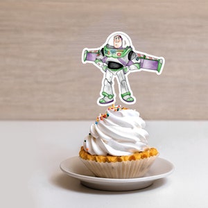 May include: A white cupcake with colorful sprinkles topped with a white frosting swirl. A cartoon image of Buzz Lightyear from the Toy Story movie is on a stick and placed on top of the cupcake.