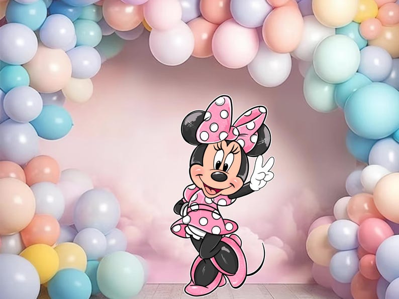 Op de afbeelding: Een cartoon illustratie van Minnie Mouse in een roze jurk en strik met stippen, die een vredesteken geeft. De achtergrond toont een roze lucht en een kleurrijke ballonnenboog in pastelkleuren, geschikt voor een verjaardagsfeest of viering.