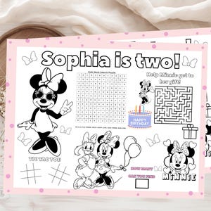 May include: Pink placemats with a Minnie Mouse theme, featuring the text "Sophia is two!" and various activities like a word search, maze, and tic-tac-toe. Includes illustrations of Minnie Mouse and birthday-themed graphics.
