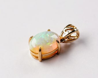 Op de afbeelding: Een gouden hanger met een witte opaal edelsteen gezet in een kraalbezetting. De hanger heeft een delicate, sierlijke bail.