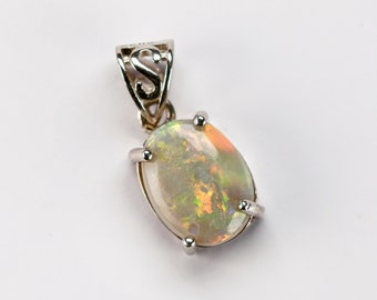Op de afbeelding: Zilveren hanger met een ovale opaal edelsteen. De opaal vertoont een kleurenspel met flitsen van oranje, groen en geel. De hanger heeft een decoratieve balein met een open ontwerp.