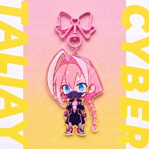 May include: A clear acrylic keychain featuring a stylized anime character with pink hair, blue eyes, and a black face mask, wearing a dark outfit. The charm is attached to a pink bow-shaped clasp. The text TALIAY CYBER is visible.