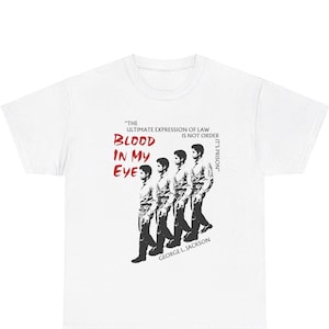 Pode incluir: Camiseta branca com um gr&aacute;fico em preto e branco de quatro homens caminhando. O gr&aacute;fico inclui o texto "The ultimate expression of law is not order, it's prison." e "Blood in my eye." em vermelho. O texto "George L. Jackson" tamb&eacute;m est&aacute; inclu&iacute;do em preto.