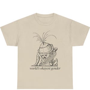 Może przedstawiać: Beżowa koszulka z czarno-białą ilustracją fantazyjnej postaci z roślinną głową i napisem "world's okayest gender". Koszulka graficzna wykonana jest z miękkiego materiału.