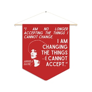 May include: A red fabric wall banner featuring a white graphic portrait of Angela Davis and the quote: I AM NO LONGER ACCEPTING THE THINGS I CANNOT CHANGE. I AM CHANGING THE THINGS I CANNOT ACCEPT. The banner hangs from a wooden dowel with a string.