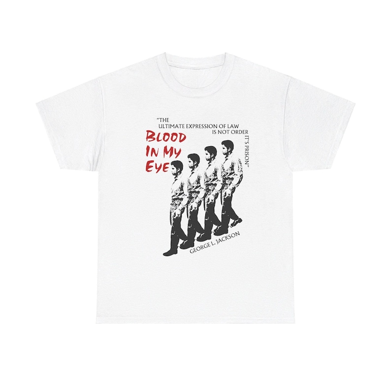 Pode incluir: Camiseta branca com um gr&aacute;fico em preto e branco de quatro homens caminhando. O gr&aacute;fico inclui o texto "The ultimate expression of law is not order, it's prison." e "Blood in my eye." em vermelho. O texto "George L. Jackson" tamb&eacute;m est&aacute; inclu&iacute;do em preto.
