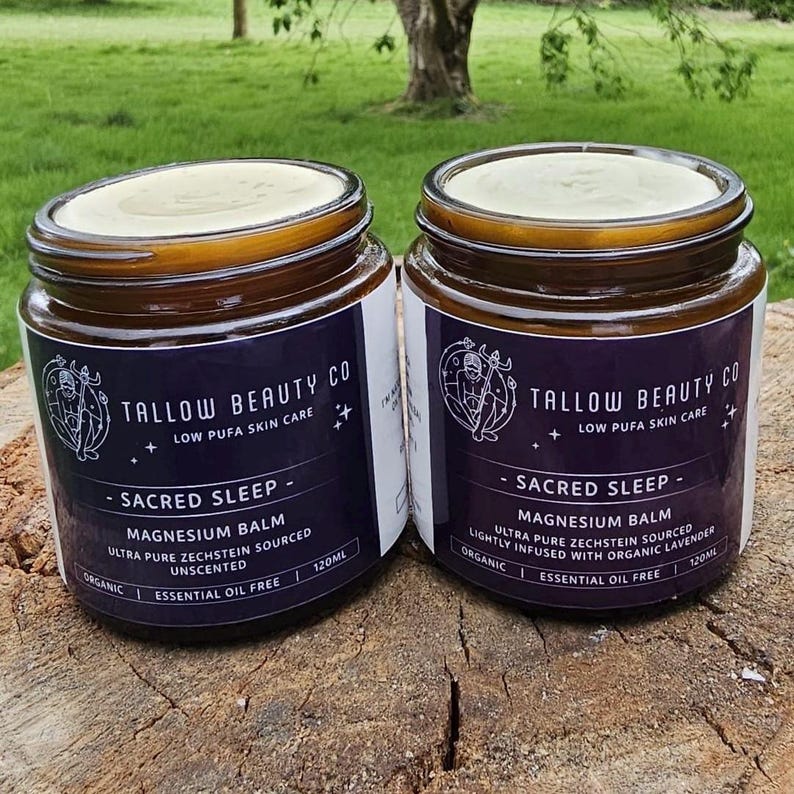 Puede incluir: Dos frascos de vidrio &aacute;mbar de b&aacute;lsamo de magnesio Sacred Sleep de Tallow Beauty Co., cada uno de 120ml. Las etiquetas muestran un logotipo circular, el texto 'Low Pufa Skin Care' y especifican 'Ultra Pure Zechstein Sourced', uno sin aroma y otro de lavanda.