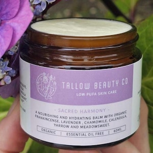 May include: A 60ml amber glass jar containing a white balm, featuring a purple label with the text Tallow Beauty Co, Low Pufa Skin Care, Sacred Harmony, and a list of organic ingredients including frankincense, lavender, and chamomile.