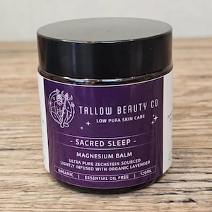 Puede incluir: Un tarro de 120ml de b&aacute;lsamo de magnesio Sacred Sleep de Tallow Beauty Co. con tapa negra y etiqueta morada. La etiqueta presenta una ilustraci&oacute;n de l&iacute;nea blanca de una figura, el texto Low Pufa Skin Care, y notas de que es org&aacute;nico y sin aceites esenciales.