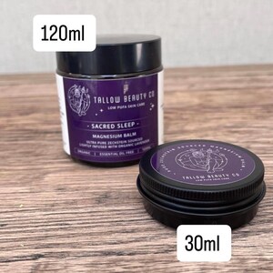 Puede incluir: Dos tarros negros de b&aacute;lsamo de magnesio de Tallow Beauty Co. El tarro m&aacute;s grande es de 120ml y est&aacute; etiquetado como Sacred Sleep, mientras que el m&aacute;s peque&ntilde;o es de 30ml. Ambos tienen etiquetas moradas con texto blanco y un gr&aacute;fico circular.
