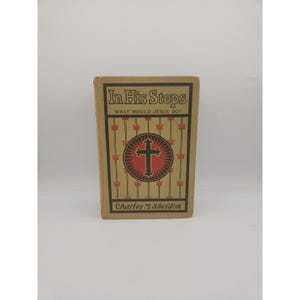May include: A vintage book titled "In His Steps" with the subtitle "What Would Jesus Do?" The cover features a cross within a circle, set against a decorative background. The author's name, Charles M. Sheldon, is printed at the bottom.
