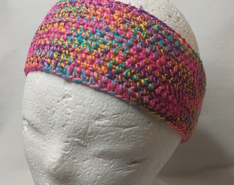 May include: A colorful crocheted headband in shades of pink, yellow, blue, and purple. The headband is made with a textured stitch and is shown on a white mannequin head.