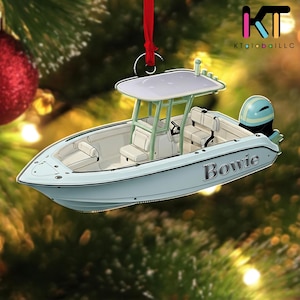May include: A light blue boat ornament with the name "Bowie" in silver lettering. The boat has a white interior, a light green frame, and a light blue motor. The ornament is hanging from a red ribbon.