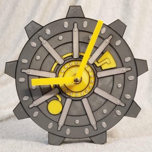 May include: A gray and yellow clock with a gear-like design. The clock features yellow hands and accents, with a circular face resembling a vault door. The clock's design includes silver details and a yellow pendulum.