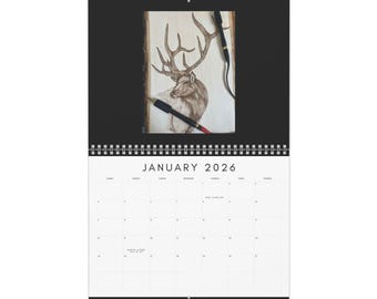 May include: A wall calendar for 2026 featuring a detailed drawing of a deer with large antlers on a wooden background. The calendar is open to January, with a simple, minimalist design. The calendar is bound with a black spiral.