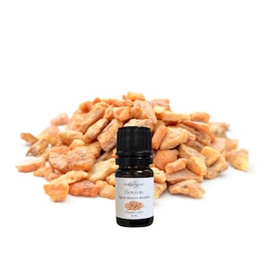 May include: A black bottle of Benzoín essential oil with a white label, beside a pile of amber-coloured resin pieces. The label reads "Benzoín Styrax Benzoin Absolut" and "Organic, pure 5 ml."