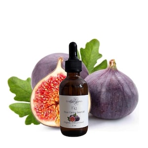 May include: A brown glass bottle with a dropper, labeled "Fig Ficus Carica Seed Oil" and "2 oz", sits in front of two purple figs and a fig half. Green leaves are in the background. The product is labeled as organic and cold-pressed.