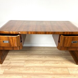 May include: A vintage wooden desk with a curved top and two drawers on each side. The desk has a rich brown wood finish and silver drawer pulls.