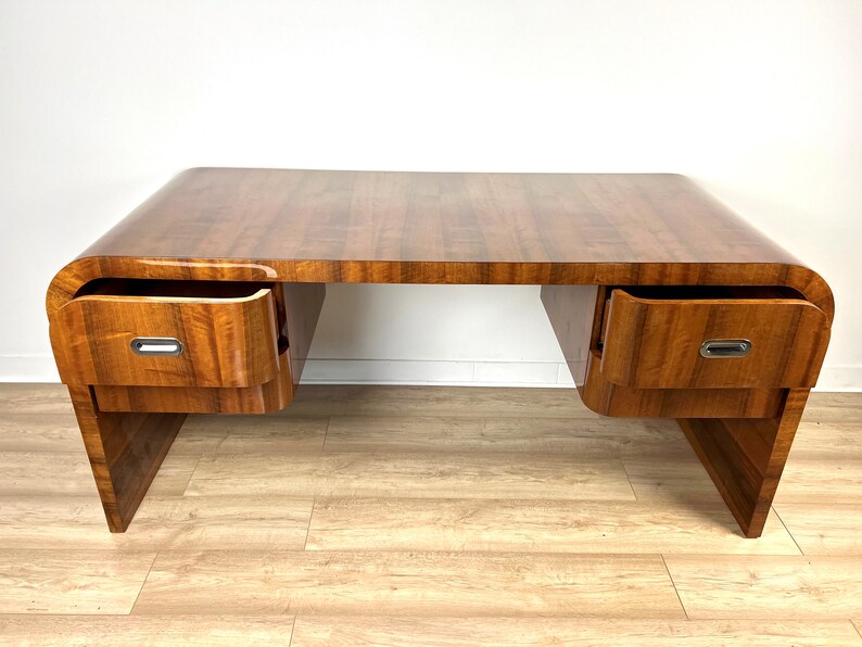 May include: A vintage wooden desk with a curved top and two drawers on each side. The desk has a rich brown wood finish and silver drawer pulls.