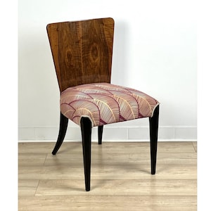 May include: A vintage wooden chair with a black frame and a patterned fabric seat. The chair has a curved back and a unique design.