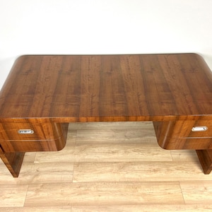 May include: A dark wood desk with a curved design and two drawers. The desk has a smooth, polished finish and a simple, modern style.