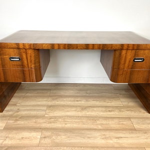 May include: A vintage wooden desk with a curved design and two drawers. The desk has a dark brown finish and silver hardware.